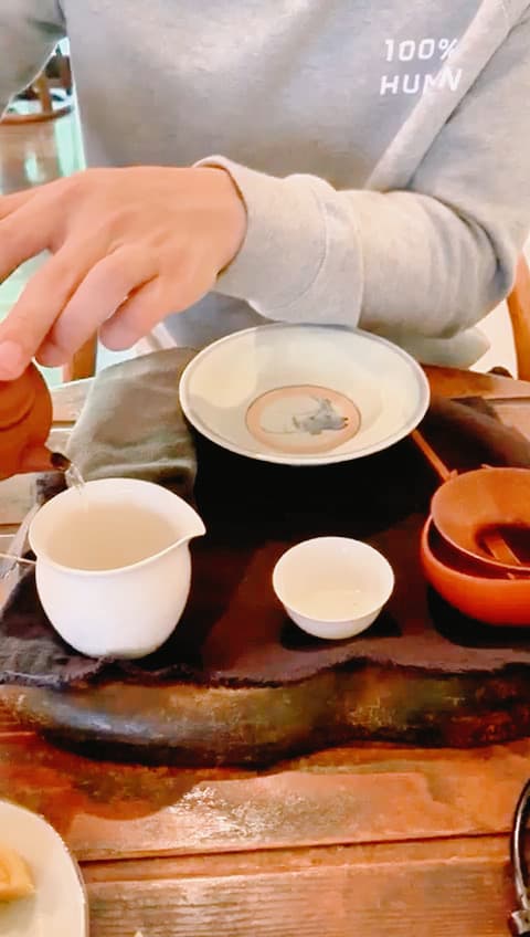 Pouring tea, gaiwan and cup on a wooden tea boat